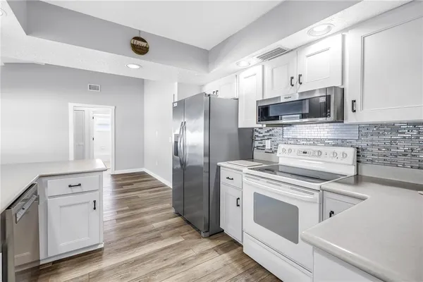 a kitchen with granite countertop white cabinets and white stainless steel appliances