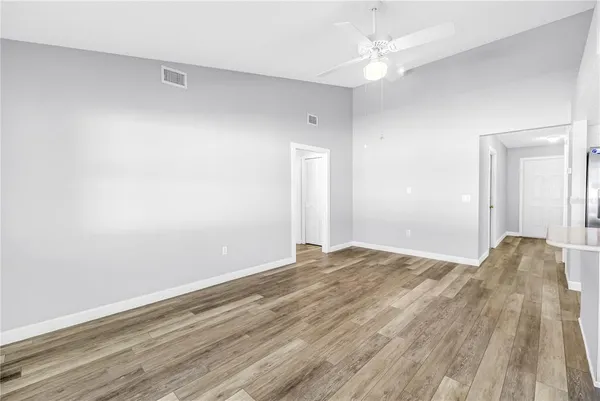 an empty room with a chandelier fan and windows