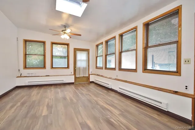 a view of an empty room with a window and wooden floor