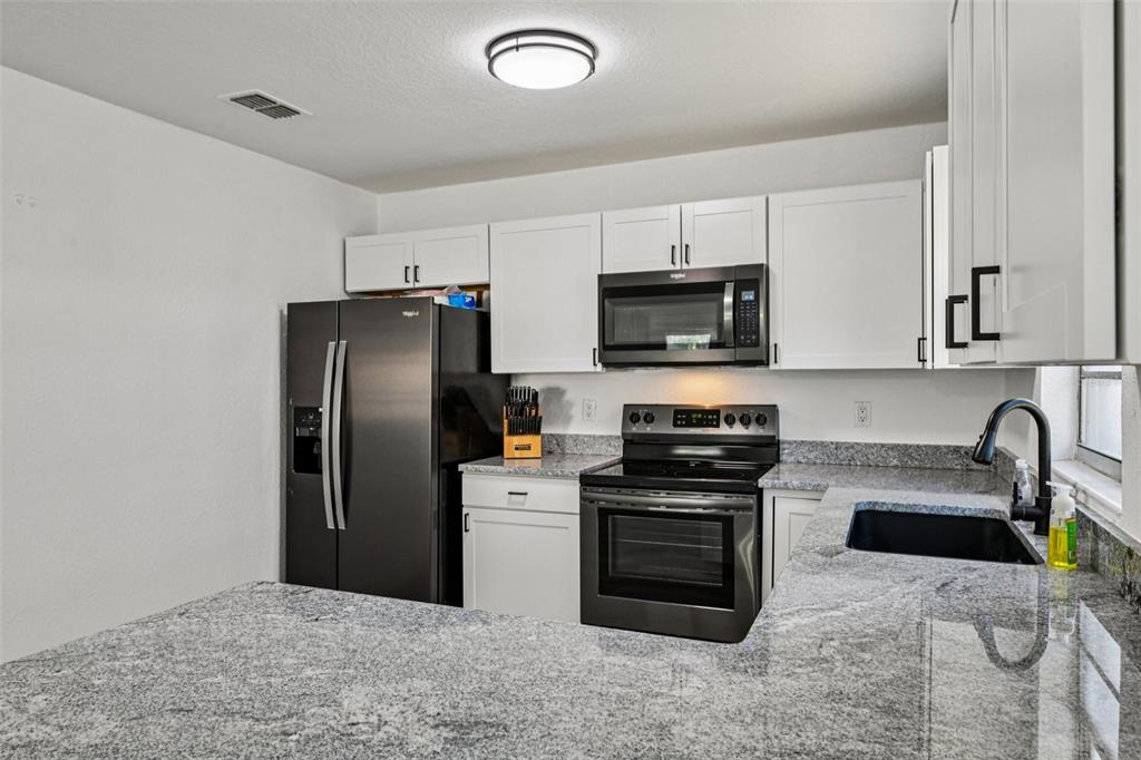 56305 Redbud Road Astor, FL 32102 - Photo 12 of 32 a kitchen with stainless steel appliances granite countertop a stove a refrigerator and a sink