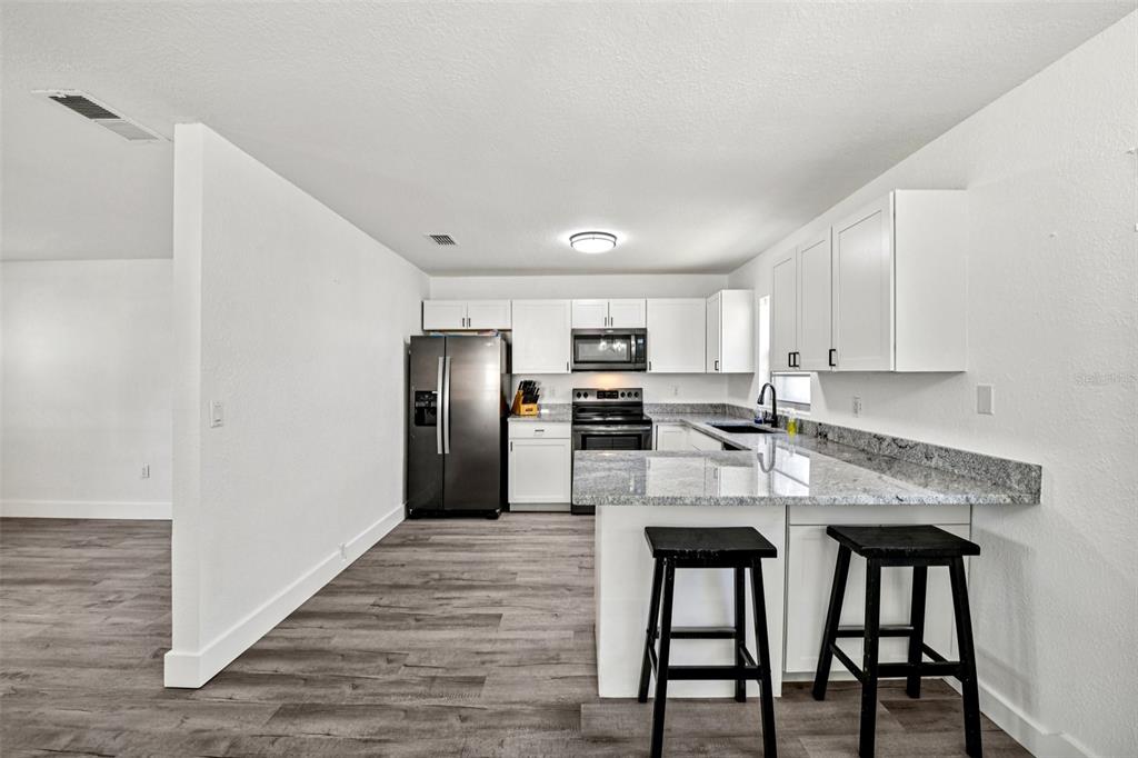 56305 Redbud Road Astor, FL 32102 - Photo 13 of 32 a kitchen with stainless steel appliances granite countertop a dining table chairs refrigerator and sink