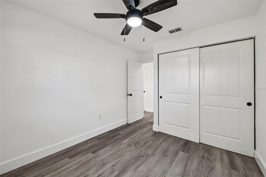 56305 Redbud Road Astor, FL 32102 - Photo 21 of 32 an empty room with wooden floor a ceiling fan and closet