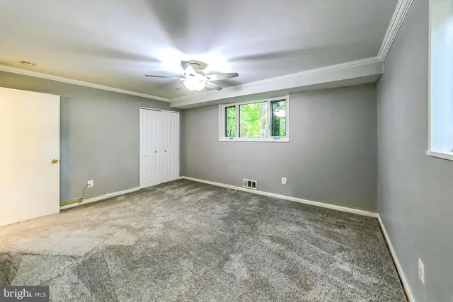 an empty room with windows and ceiling fan