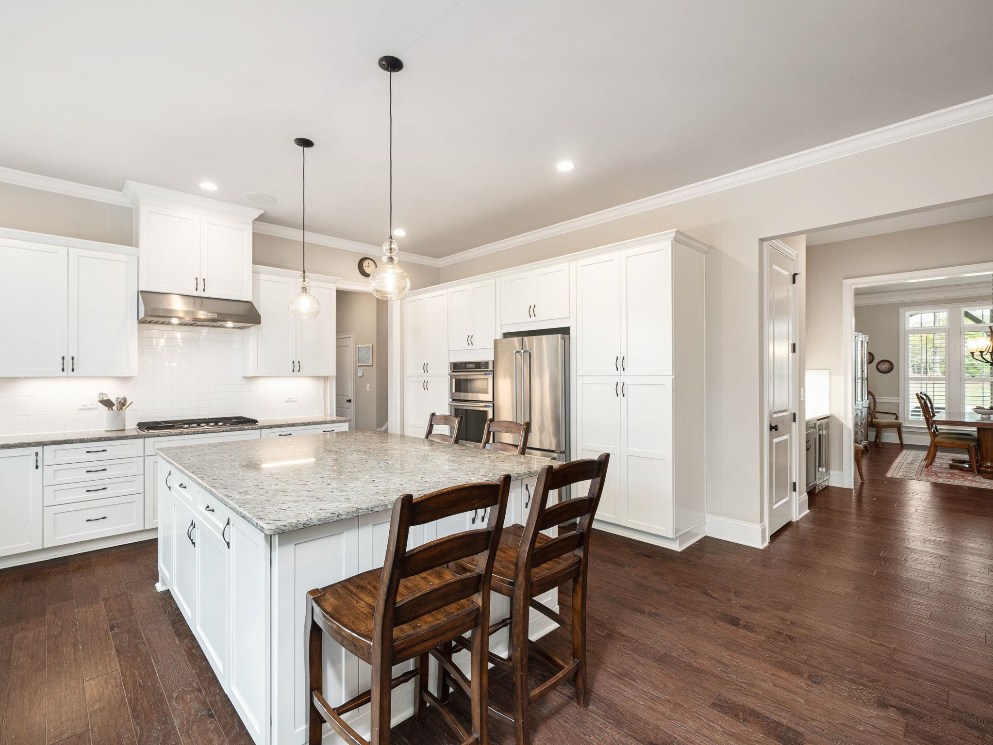 7532 Hasentree Way Wake Forest, NC 27587 - Photo 11 of 40 a kitchen with stainless steel appliances granite countertop a stove a sink a refrigerator a dining table and chairs with wooden floor