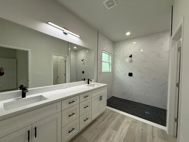 a bathroom with a double vanity sink a mirror and a shower