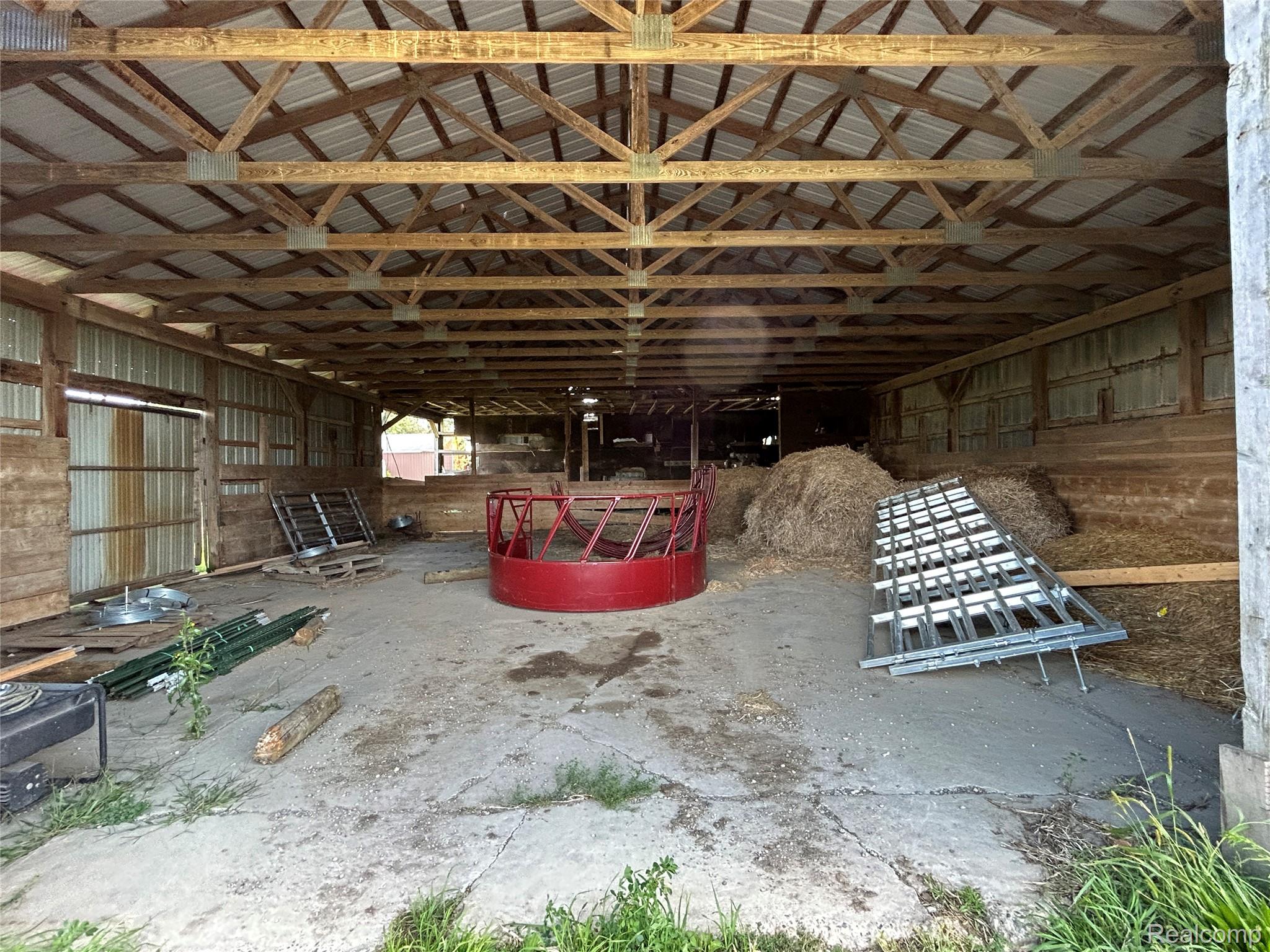 16465 Almont Road Allenton, MI 48002 - Photo 35 of 35 Open-sided barn structure featuring exposed wood trusses, metal roofing, and a concrete floor