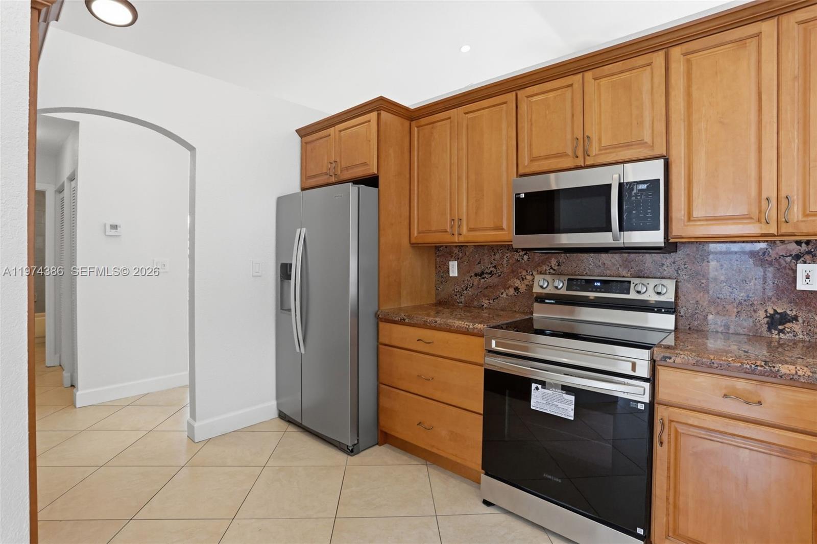 12930 Southwest 20th Street Miramar, FL 33027 - Photo 13 of 48 a kitchen with stainless steel appliances granite countertop a stove microwave and refrigerator