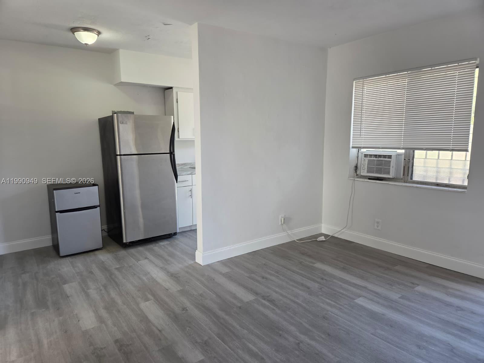 1628 Southwest 7th Street, Unit 8 Miami, FL 33135 - Photo 2 of 8 a view of an empty room with wooden floor and a window