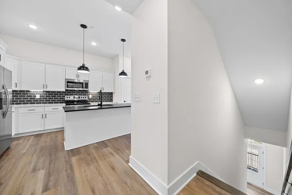 a kitchen with stainless steel appliances granite countertop a refrigerator a stove and white cabinets with wooden floor