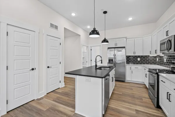 a kitchen with stainless steel appliances granite countertop a sink a stove and a refrigerator