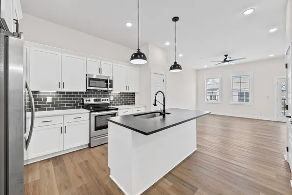 a kitchen with stainless steel appliances granite countertop a sink a stove and a wooden floors