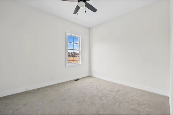 an empty room with a window and ceiling fan