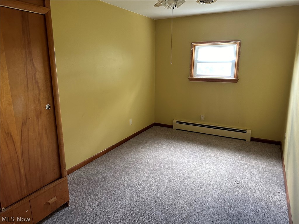 2288 Martin Road Mogadore, OH 44260 - Photo 9 of 27 Unfurnished room featuring carpet flooring, ceiling fan, and a baseboard heating unit