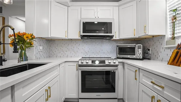 a kitchen with stainless steel appliances granite countertop a sink a stove and microwave