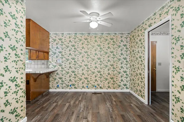 an empty room with wooden floor and a chandelier fan