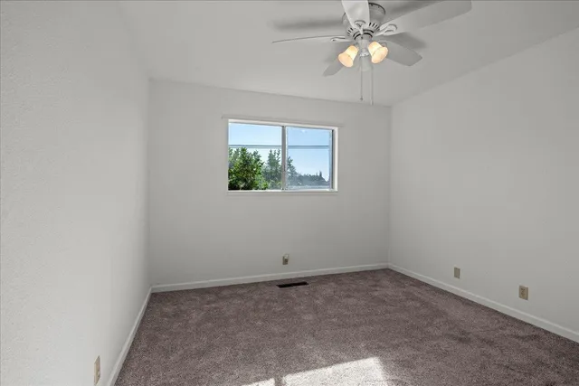 an empty room with a window and a fan