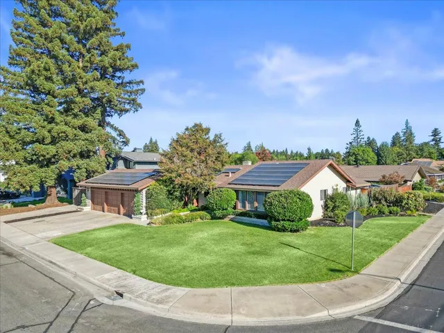a view of a house with a big yard plants and large trees