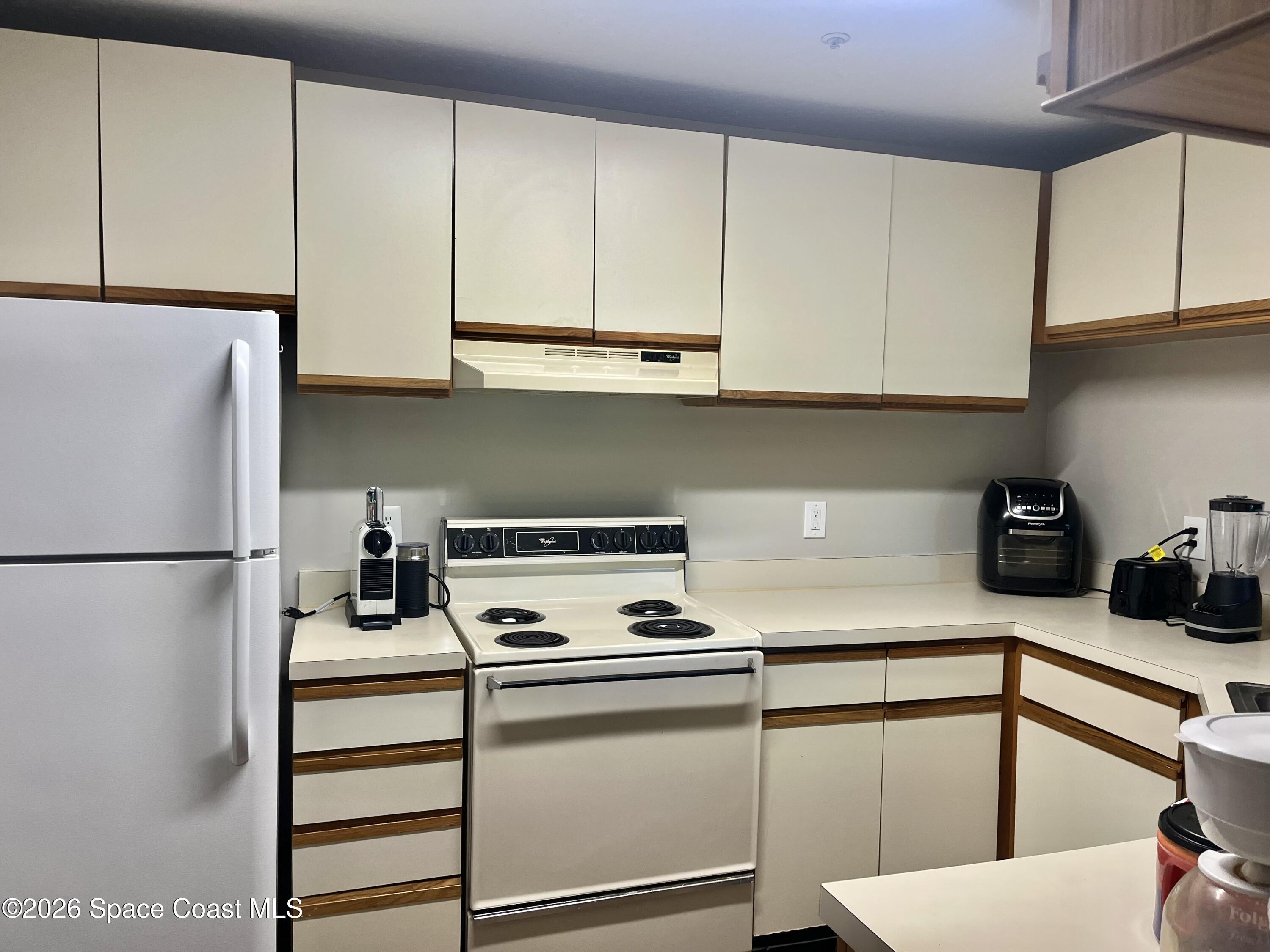 7667 North Wickham Road, Unit 1118 Melbourne, FL 32940 - Photo 2 of 26 a kitchen with a refrigerator and cabinets