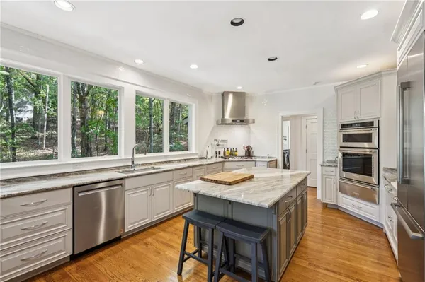 a large kitchen with kitchen island a large window a sink and stainless steel appliances