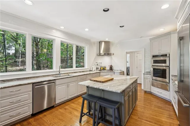 a large kitchen with kitchen island a large window a sink and stainless steel appliances