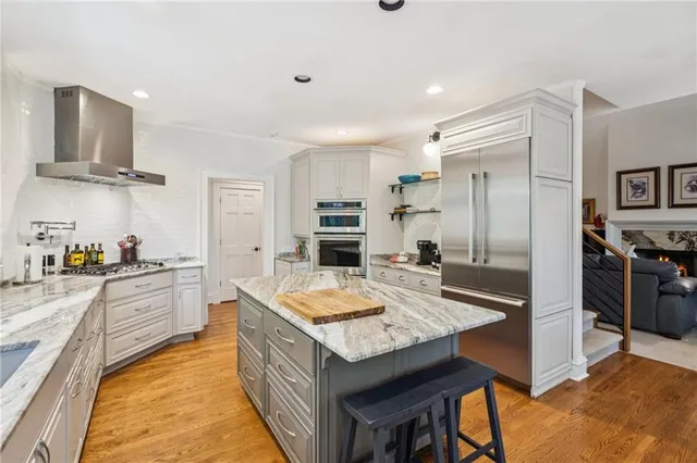 a kitchen with granite countertop a stove a sink a dining table and chairs with wooden floor