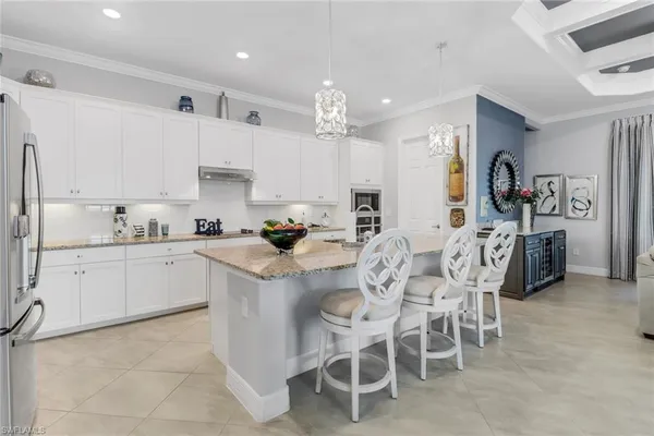 a kitchen with stainless steel appliances kitchen island granite countertop a table chairs sink and cabinets