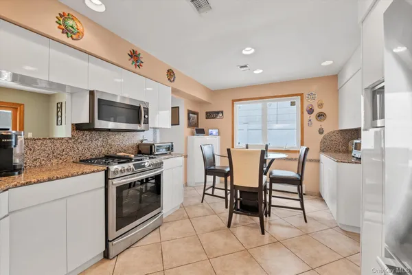 a kitchen with stainless steel appliances granite countertop a stove top oven a sink dishwasher a dining table and chairs with wooden floor