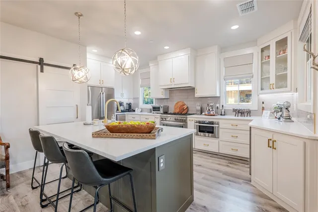 a kitchen with stainless steel appliances granite countertop a sink a stove a refrigerator and island with wooden floor