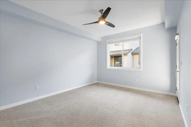 an empty room with a ceiling fan and a window