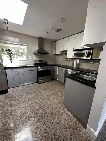 a kitchen with granite countertop a sink dishwasher stove and white cabinets