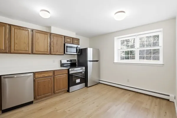 a kitchen with stainless steel appliances granite countertop a stove a sink dishwasher a refrigerator and a microwave oven on the wooden floor