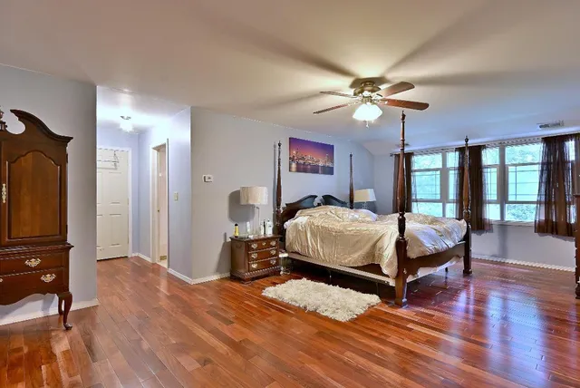 a bedroom with a bed dresser and a large window