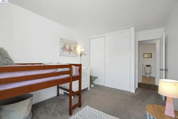 a bedroom with a bed and a lamp on dresser