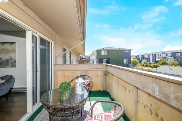 a balcony with glass top table and chairs