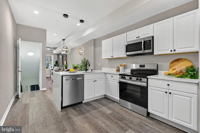 a kitchen with white cabinets stainless steel appliances and wooden floor
