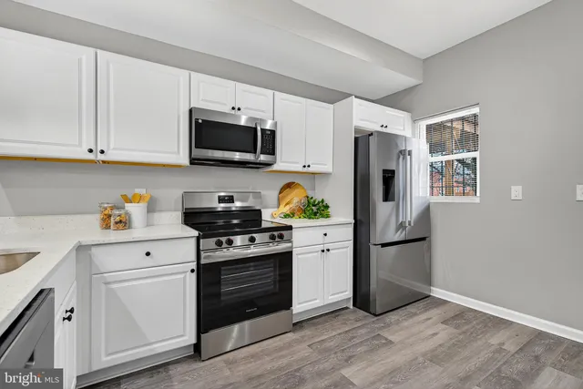 a kitchen with stainless steel appliances granite countertop a refrigerator stove and white cabinets