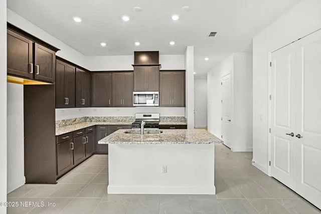 a kitchen with stainless steel appliances granite countertop a refrigerator a sink and a stove