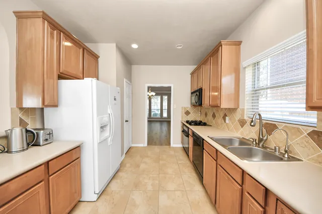 a large kitchen with a sink large window and stainless steel appliances