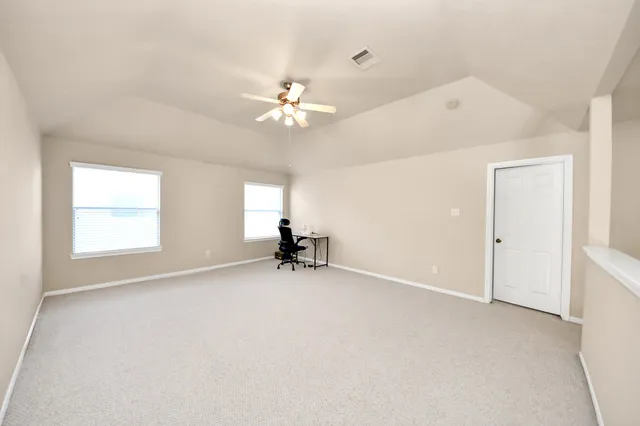 an empty room with windows and fan