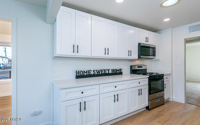 630 Solana Avenue Ajo, AZ 85321 - Photo 6 of 41 a kitchen with white cabinets and black appliances
