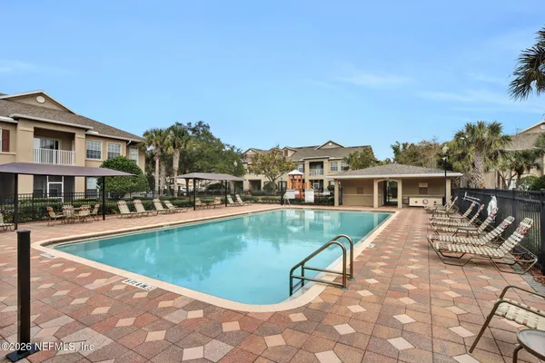 a view of a house with pool lawn chairs and a yard