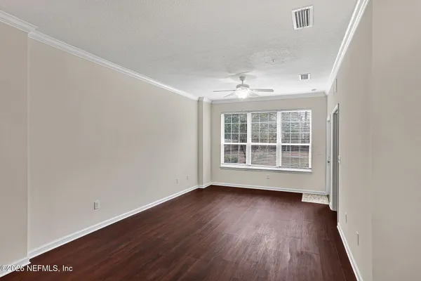 an empty room with wooden floor and windows
