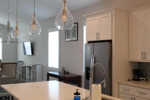 a kitchen with stainless steel appliances granite countertop a refrigerator a sink dishwasher a dining table and chairs with wooden floor