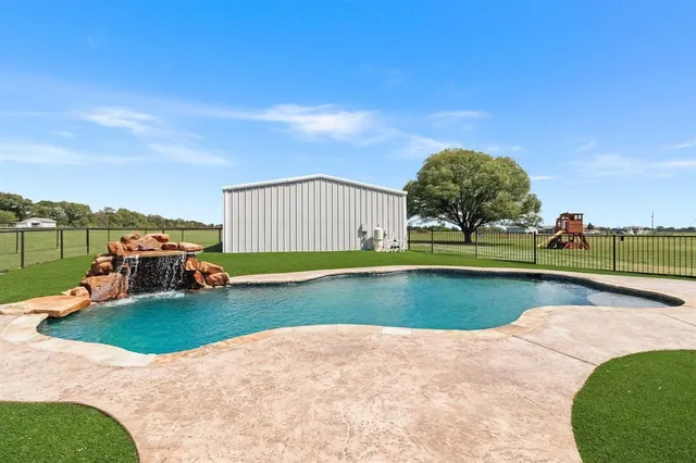 a view of a swimming pool with lawn chairs and a big yard