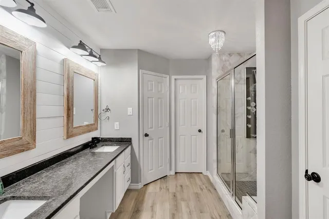 a bathroom with a granite countertop sink a mirror and shower