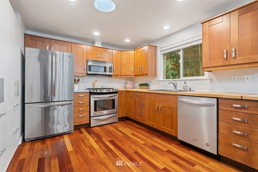 5680 Northeast Foster Road Bainbridge Island, WA 98110 - Photo 3 of 23 a kitchen with granite countertop wooden floors stainless steel appliances a sink and a window