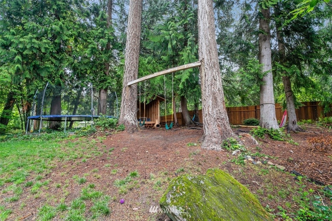 5680 Northeast Foster Road Bainbridge Island, WA 98110 - Photo 21 of 23 a view of a backyard with large trees and wooden fence