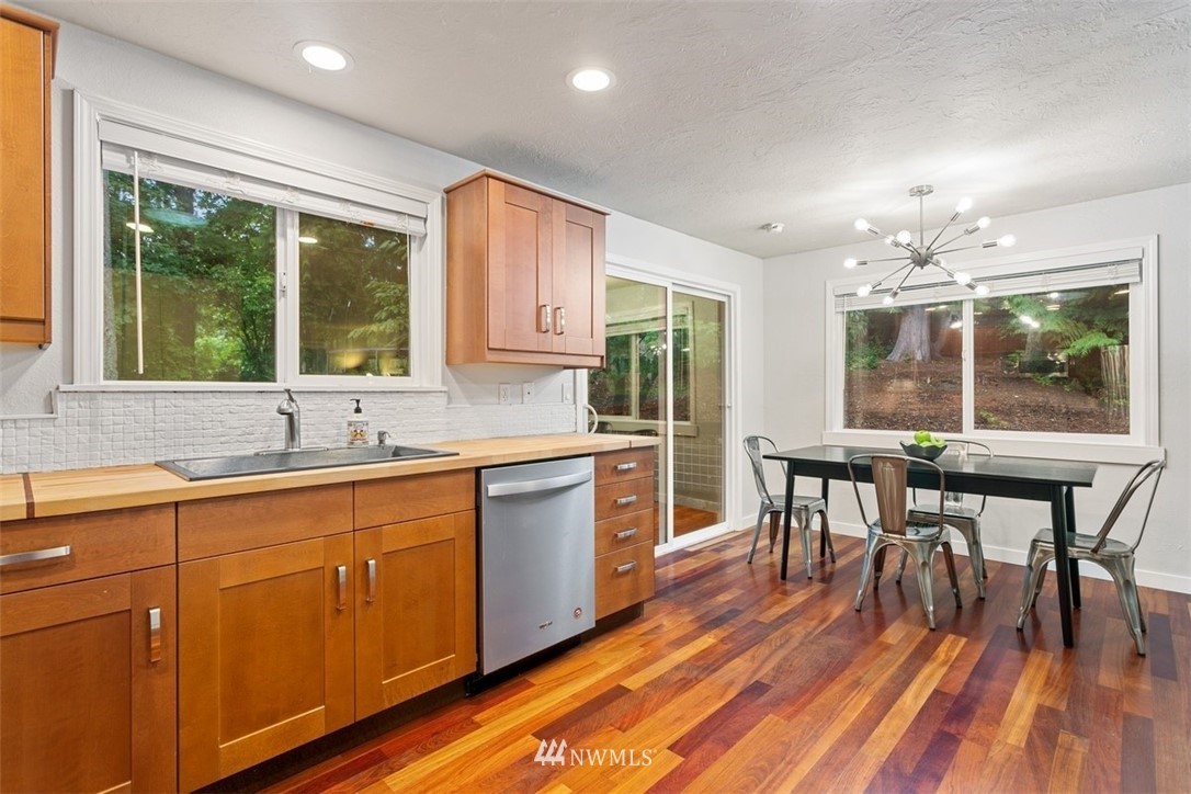 5680 Northeast Foster Road Bainbridge Island, WA 98110 - Photo 4 of 23 a kitchen with stainless steel appliances granite countertop wooden floor a dining table and chairs