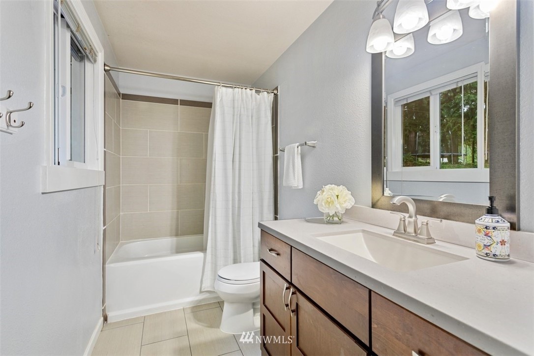 5680 Northeast Foster Road Bainbridge Island, WA 98110 - Photo 9 of 23 a bathroom with a granite countertop sink a toilet and shower