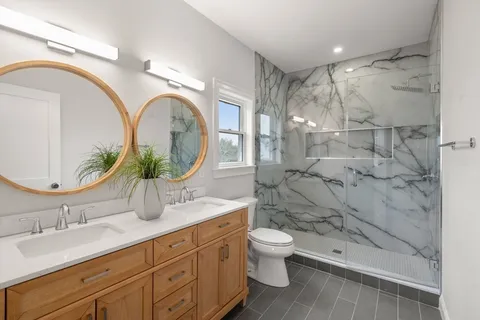 a bathroom with a granite countertop sink a mirror and shower